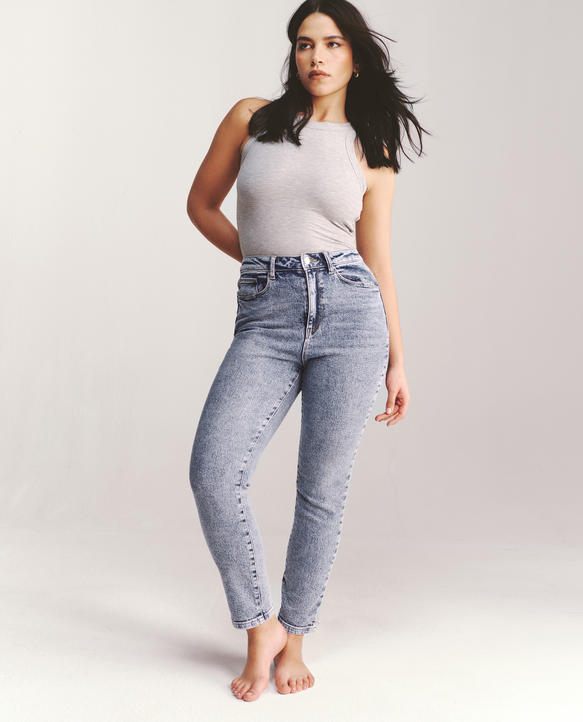 Model wearing slim mom jeans (mid blue) with vest top